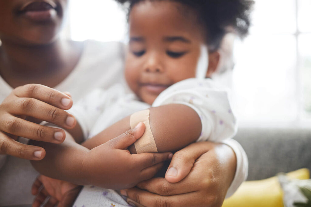 A woman holding a child who is wearing a bandage